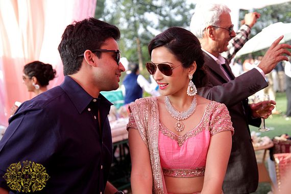 A picture of a bride and a groom in dark shaded. Another person dancing in the background.